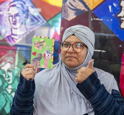 A woman holds a postcard with the slogan 'keep families together'