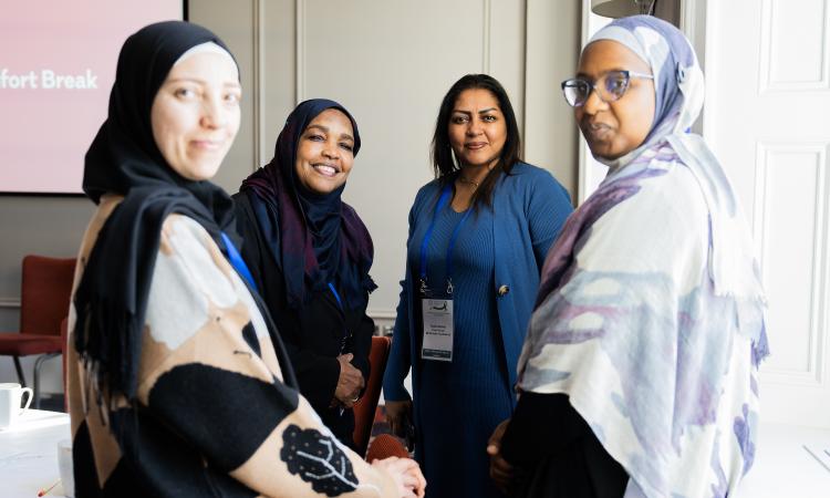 Four women smiling facing the camera at a conference