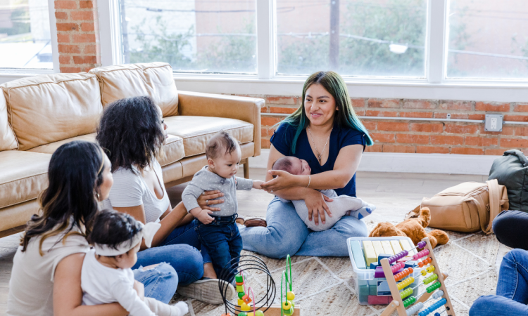 4 mums and babies sit together on the floor playing
