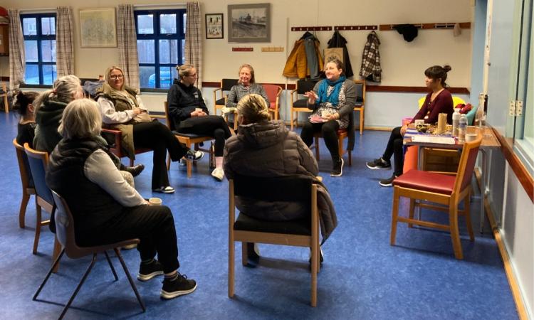 A circle of women sat indoors talking
