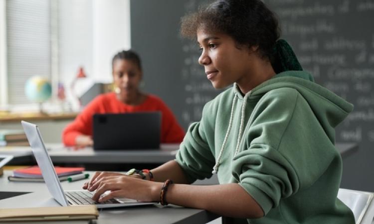 A teenage girl uses a laptop in her classroom